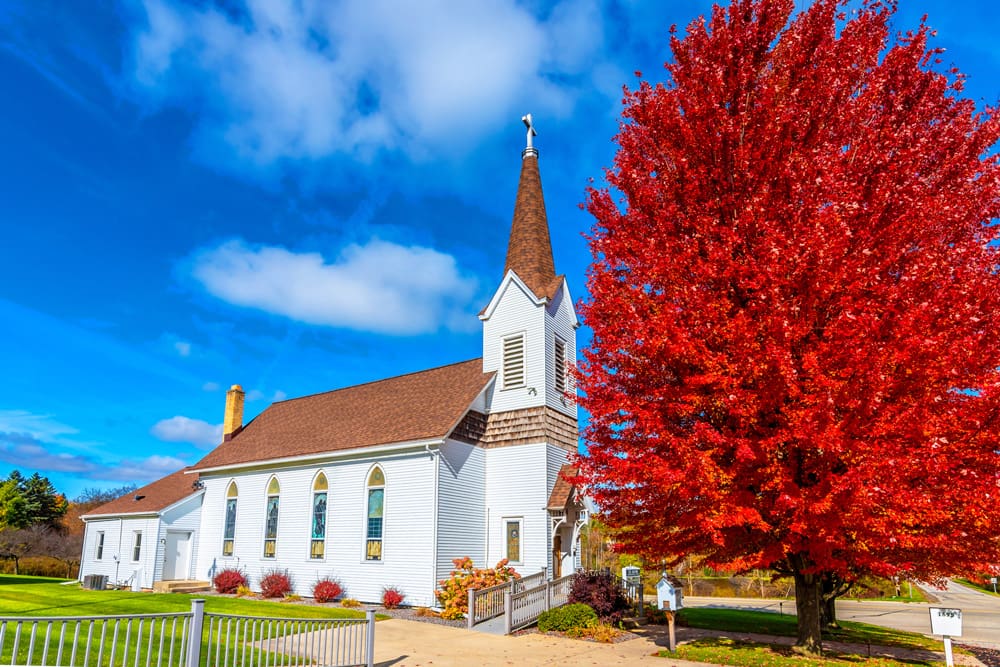church with beautiful tree covered in red leaves out front